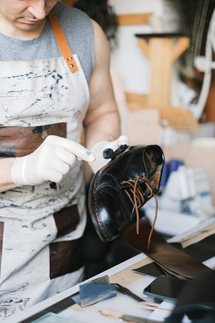 Close-up of a craftsman polishing a leather shoe in a workshop, focusing on detail and craftsmanship.