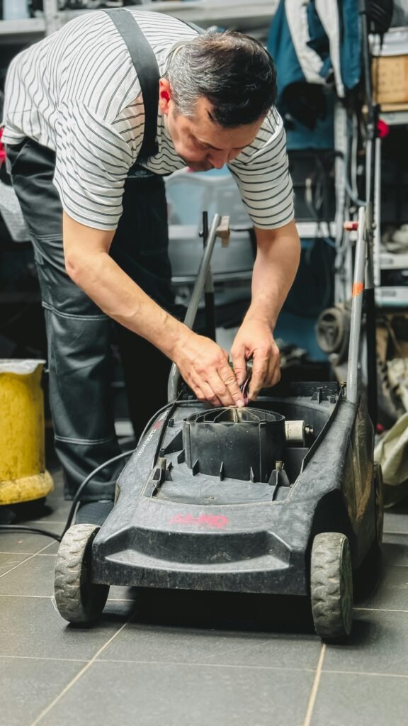 pexels-photo-32208767-32208767 Adult repairing a lawn mower in a garage workshop, focused on maintenance and DIY repair.